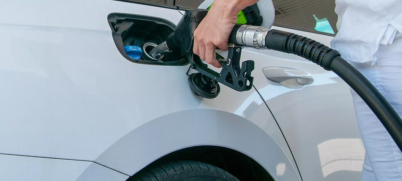 En hvit bil som får påfyll av drivstoff