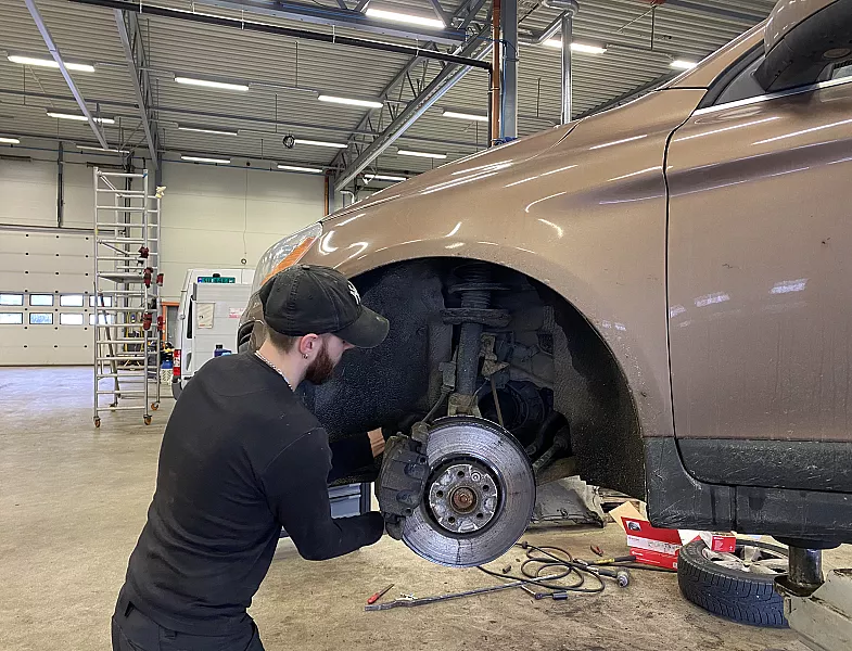 Bilmekaniker som jobber med en bil hos Tellnes Autosenter